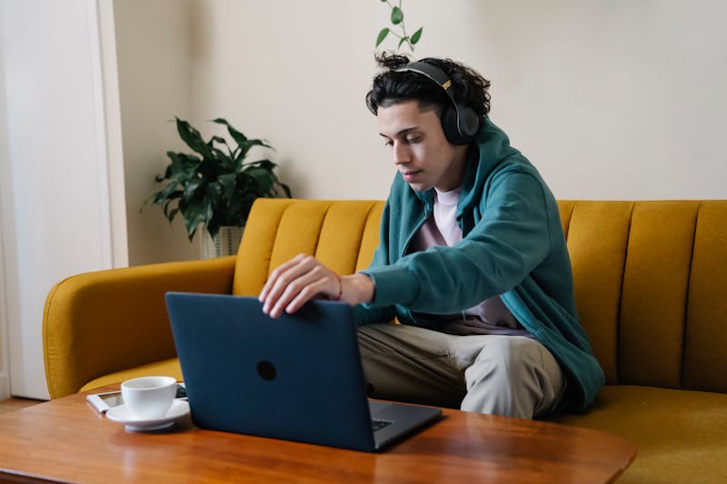 Person relaxing on couch with headphones and laptop in lounge area