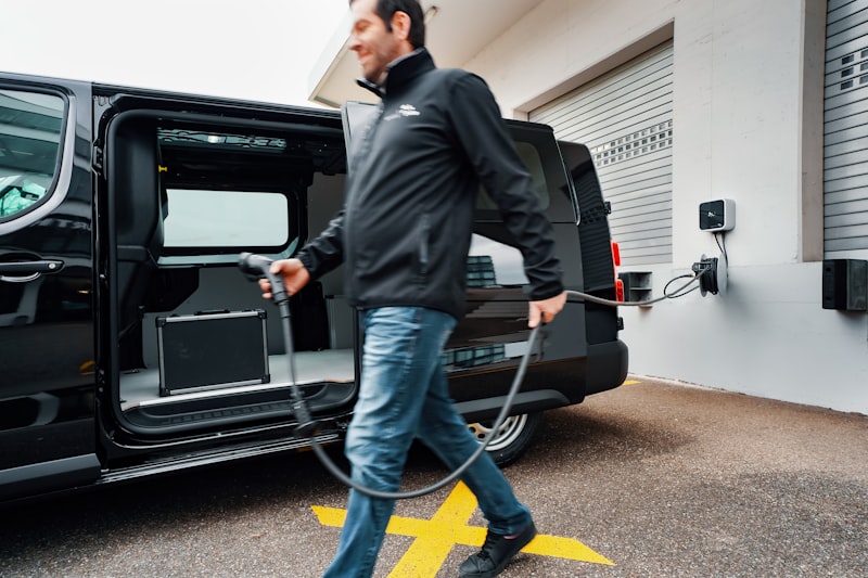 Fleet driver connecting CCS cable to commercial electric van at charging depot