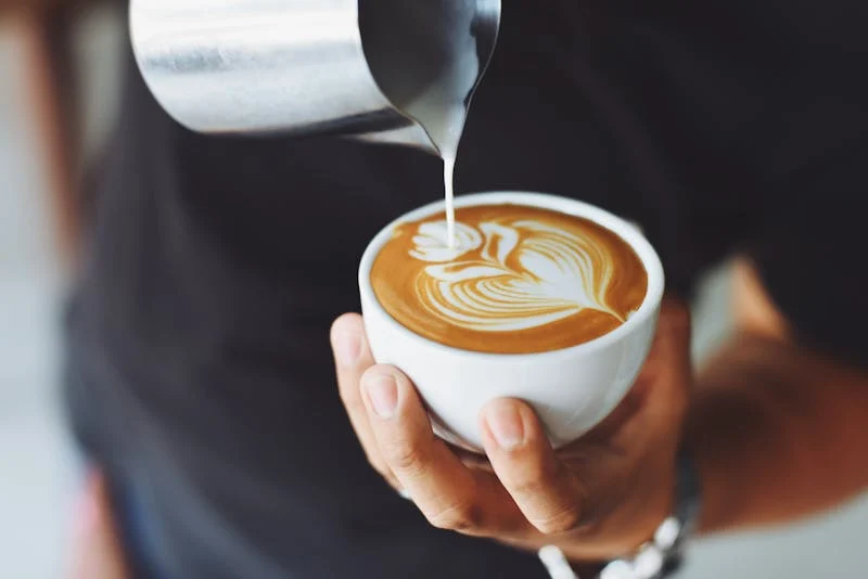 Barista pouring latte art into a coffee cup